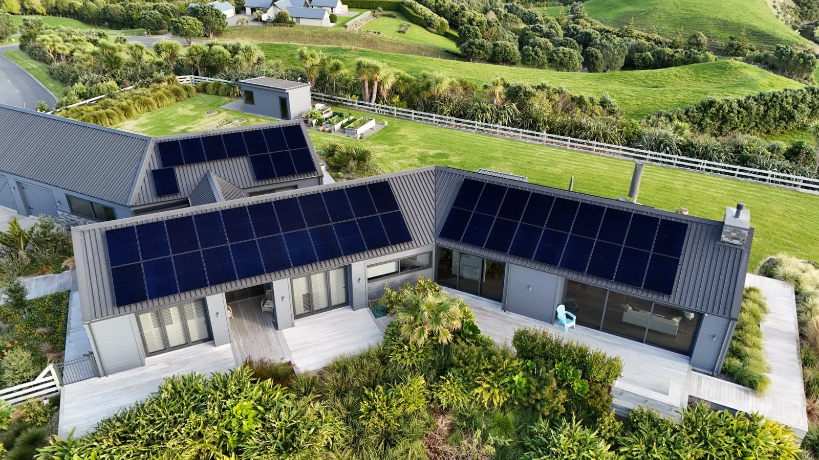 Modern Taranaki home with rooftop solar panels, set in the green coastal hills
